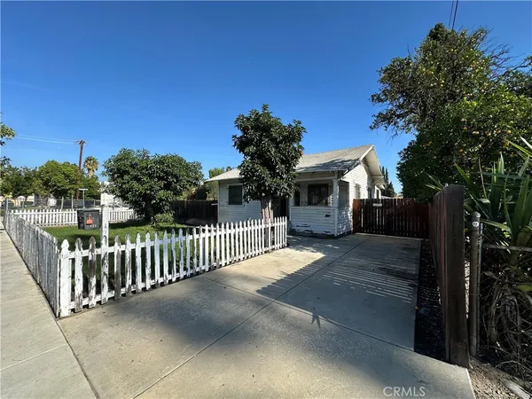 a view of a house with a small yard and a large tree