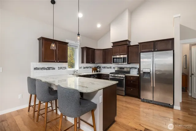 a kitchen with stainless steel appliances kitchen island granite countertop a sink a stove a refrigerator and island