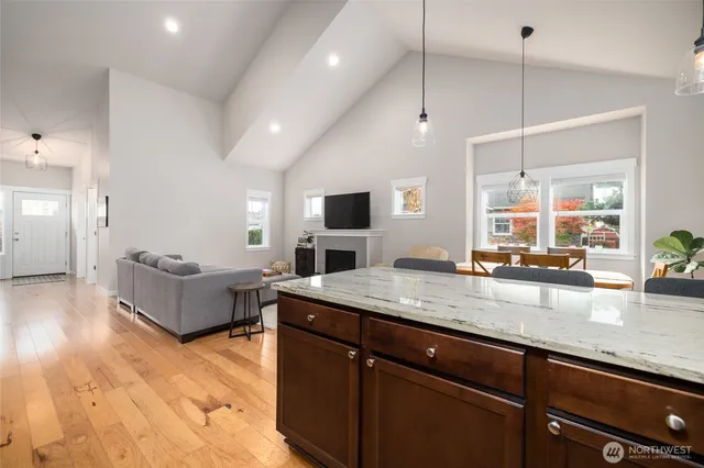 a living room with stainless steel appliances granite countertop couches a flat screen tv and kitchen island