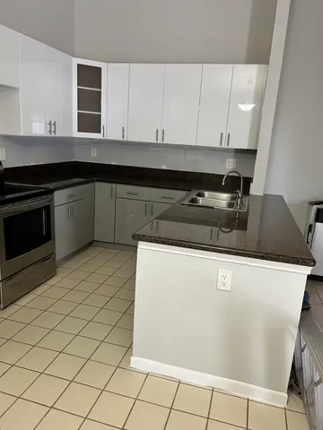 a kitchen with granite countertop a sink a stove and cabinets