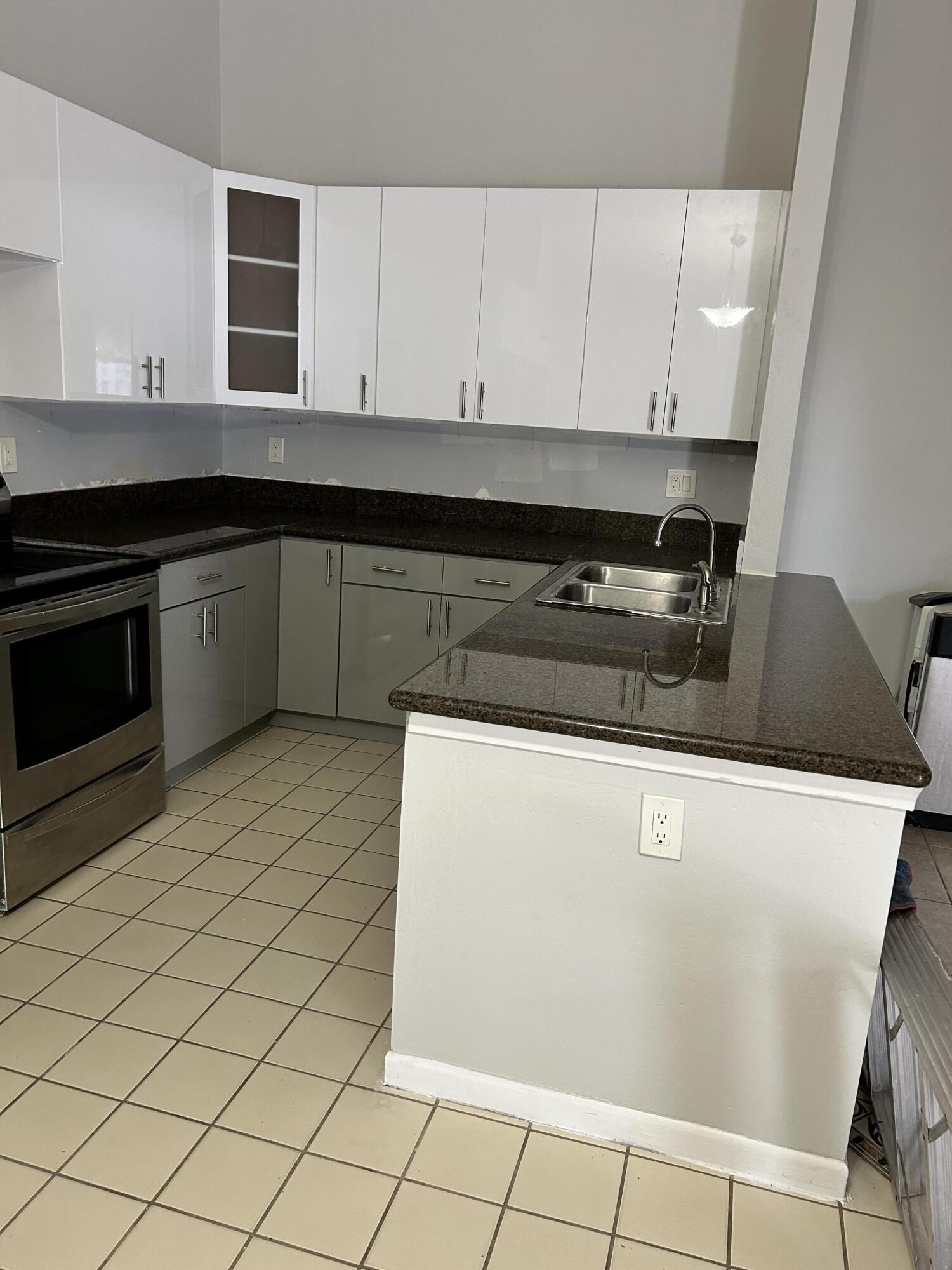 1158 Summit Trail Circle, Unit D West Palm Beach, FL 33415 - Photo 7 of 10 a kitchen with granite countertop a sink a stove and cabinets