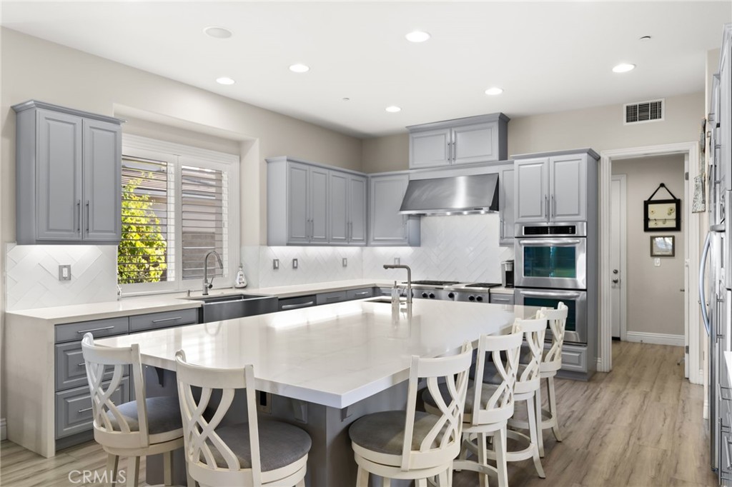 4947 Palomino Place Rancho Cucamonga, CA 91737 - Photo 11 of 53 a kitchen with stainless steel appliances kitchen island granite countertop a table chairs and a refrigerator