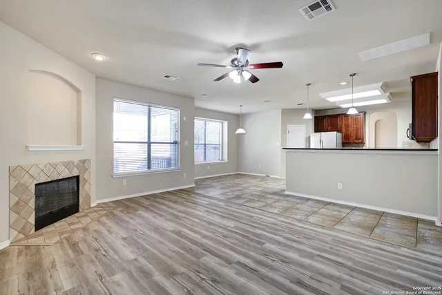 a view of a livingroom with a fireplace a ceiling fan and wooden floor