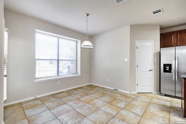 a view of an empty room with window and chandelier fan