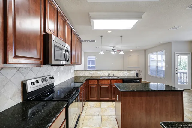 a kitchen with granite countertop a sink a stove counter space and cabinets