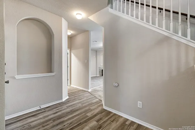 a view of a hallway with wooden floor and a bathroom