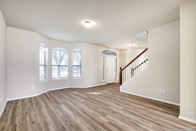 a view of empty room with wooden floor and fan