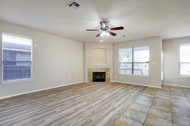 an empty room with windows and fireplace
