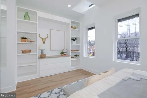 a room with a bed cabinets and window