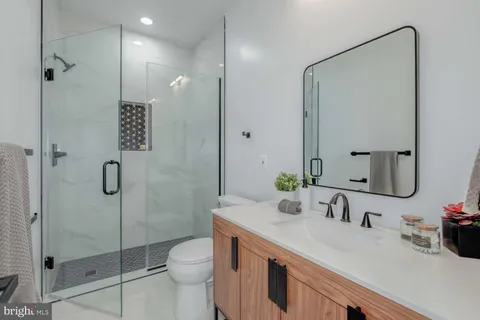 a bathroom with a granite countertop sink a toilet and shower