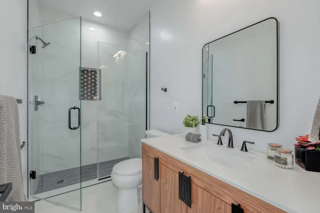 a bathroom with a granite countertop sink a toilet and shower