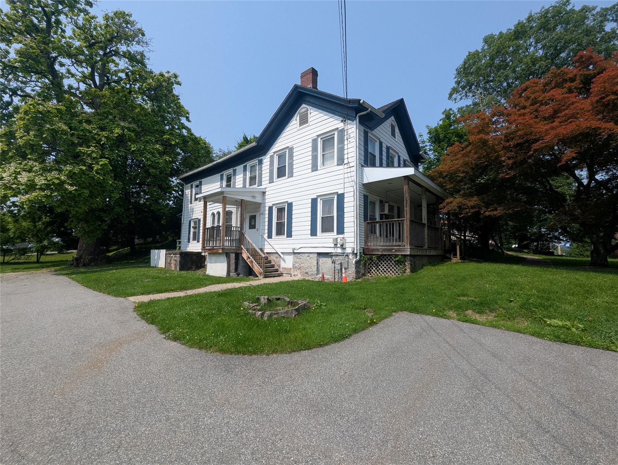 View of property exterior featuring a chimney, a yard, and covered porch