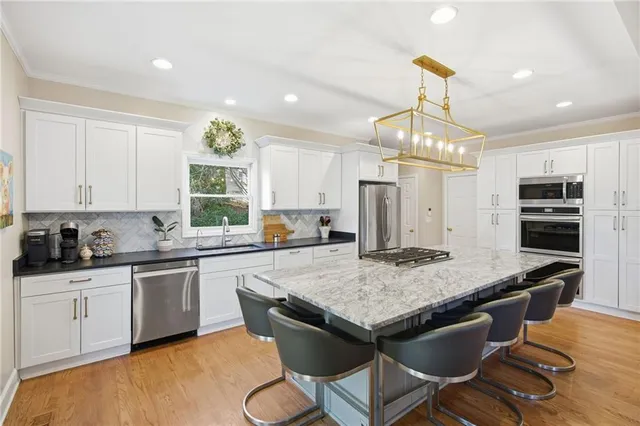 a kitchen with kitchen island granite countertop a sink a counter space appliances and cabinets