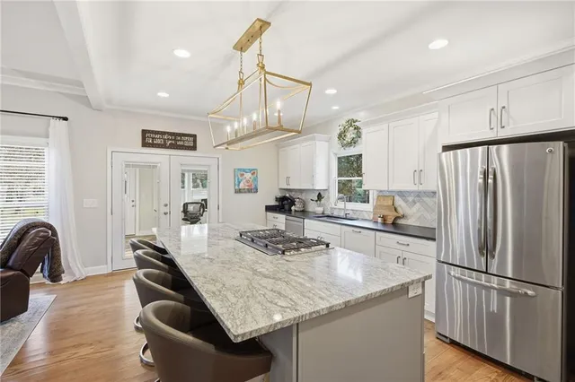 a kitchen with granite countertop a refrigerator a stove a sink dishwasher a dining table and chairs with wooden floor