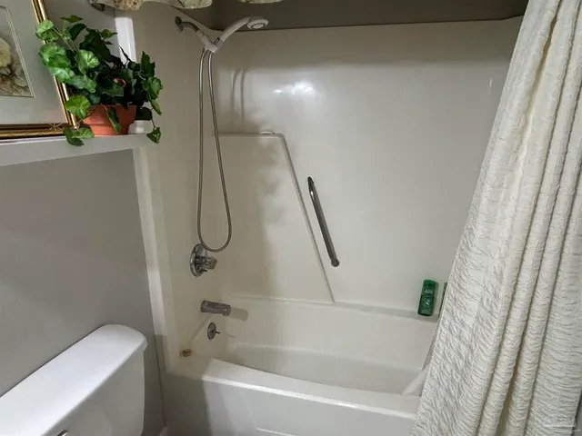 a bathroom with a granite countertop bathtub shower and toilet