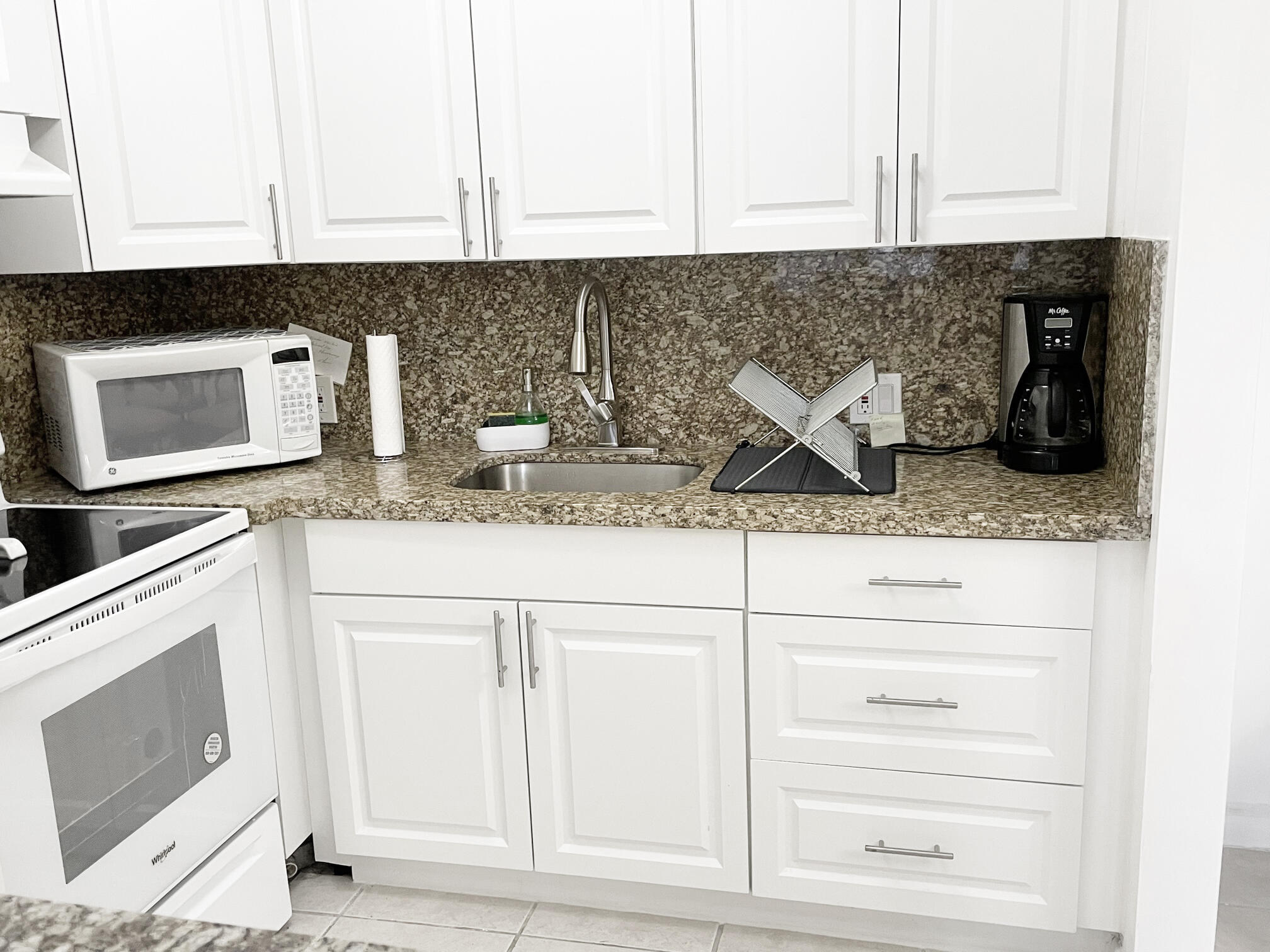 171 Suffolk F, Unit 171 Boca Raton, FL 33434 - Photo 8 of 21 a kitchen with granite countertop white cabinets and stainless steel appliances