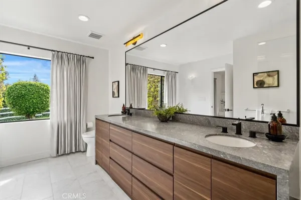 a bathroom with double vanity sinks a large mirror and a shower