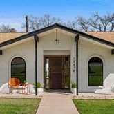 a view of a house with large windows and a yard with plants