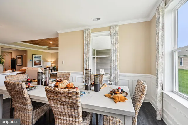a dining room with furniture large windows and a wooden floor