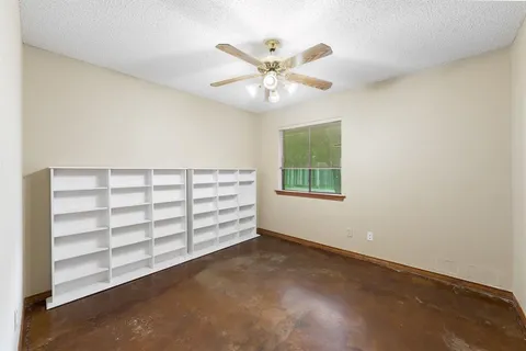 an empty room with windows and ceiling fan