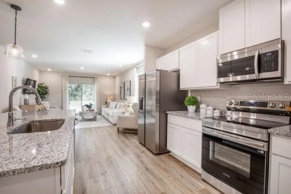a kitchen with stainless steel appliances granite countertop a stove a sink dishwasher a microwave oven and a refrigerator with wooden floor