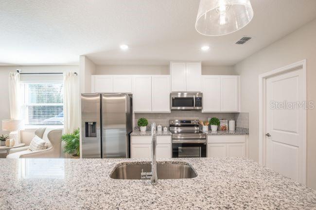 1407 Needle Palm Drive Edgewater, FL 32132 - Photo 6 of 28 a kitchen with stainless steel appliances kitchen island granite countertop a refrigerator sink and stove