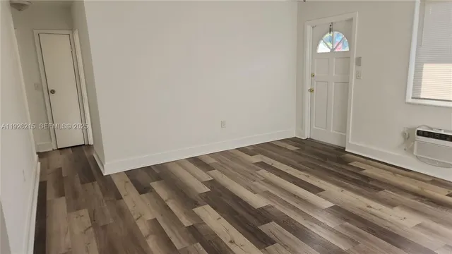 a view of empty room with window and wooden floor