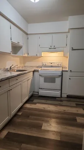 a kitchen with granite countertop white cabinets and white appliances
