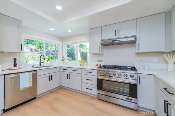 a kitchen with stainless steel appliances granite countertop a stove and white cabinets
