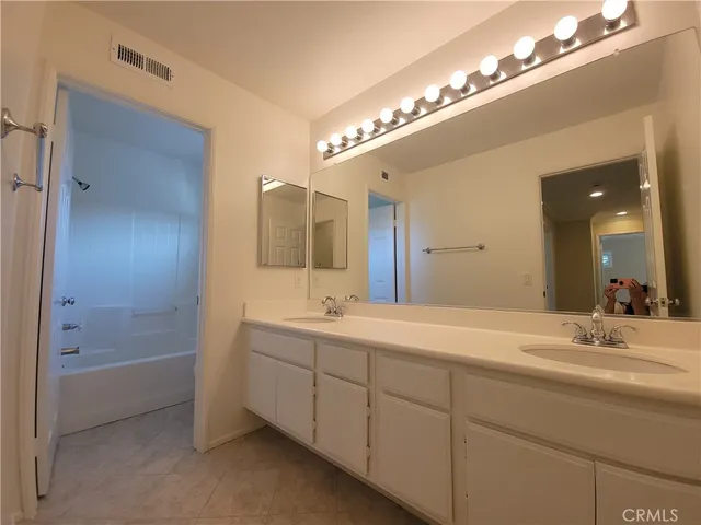 a spacious bathroom with a double vanity sink a large mirror and a bathtub