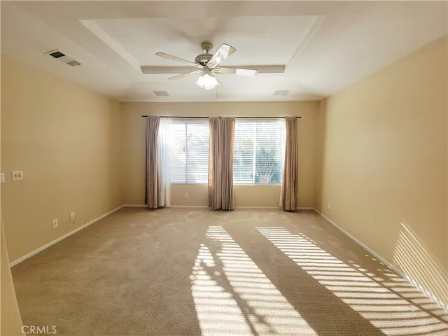 a view of an empty room with window and chandelier fan