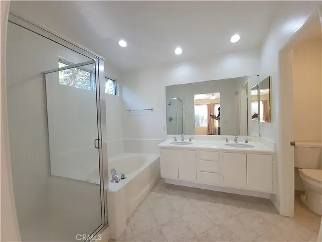 a bathroom with a bathtub a double vanity sink and mirror