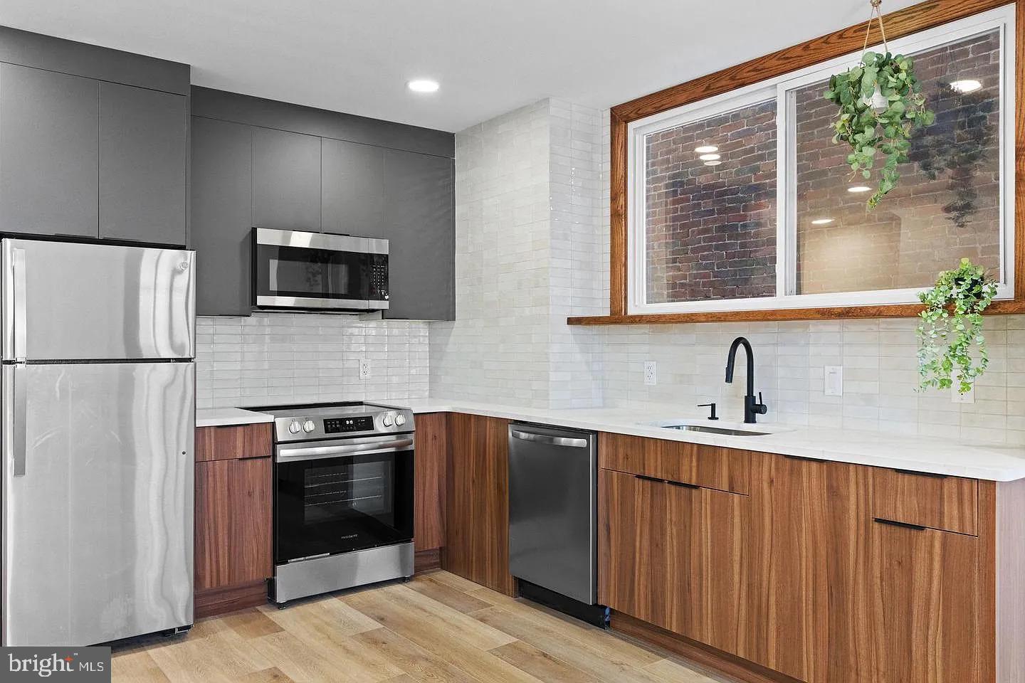1502 South 52nd Street, Unit A Philadelphia, PA 19143 - Photo 3 of 13 a kitchen with stainless steel appliances granite countertop a stove a sink and a refrigerator