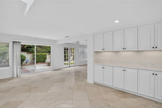 a large white kitchen with granite countertop a sink and cabinets