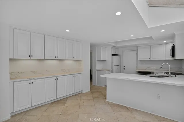 a kitchen with granite countertop a sink and white cabinets