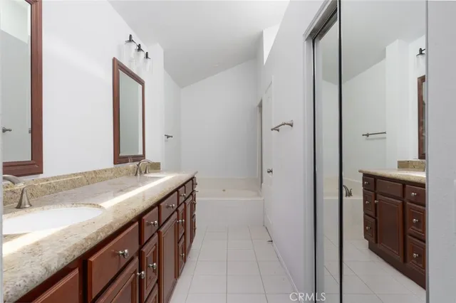 a spacious bathroom with a double vanity sink a mirror and a bathtub