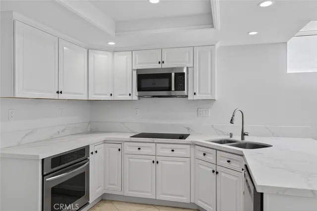 a kitchen with stainless steel appliances granite countertop a sink a microwave a stove and white cabinets
