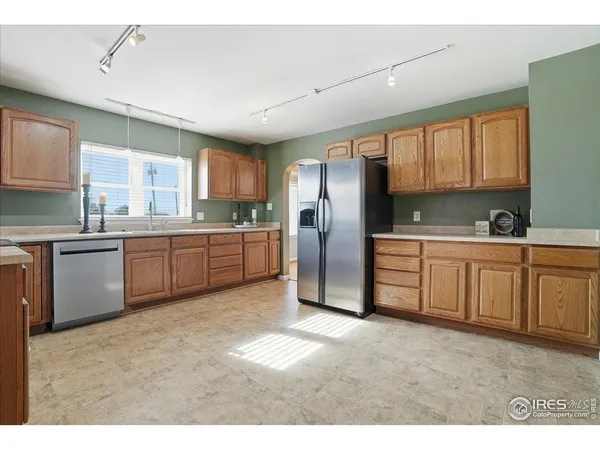 a kitchen with stainless steel appliances a sink a stove a refrigerator cabinets and a window