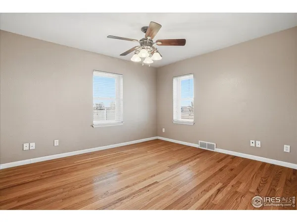 a view of an empty room with window and wooden floor