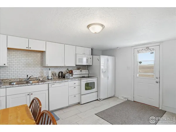 a kitchen with granite countertop a stove a sink and a refrigerator