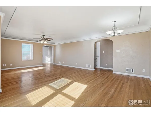 a view of an empty room with a window and wooden floor