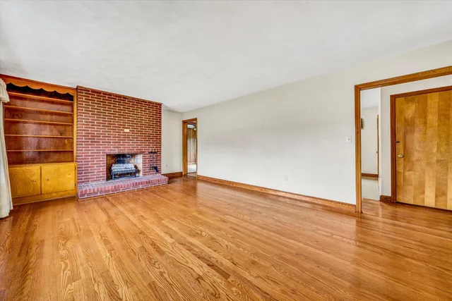 a view of empty room with wooden floor and fireplace