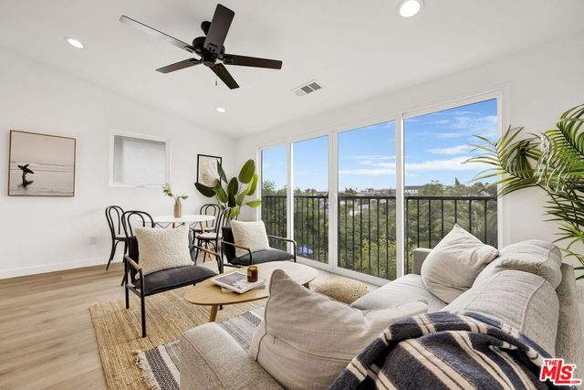 a living room with furniture ceiling fan and a large window