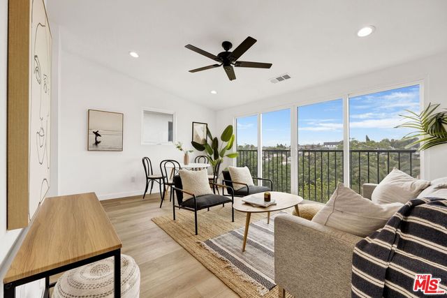 a living room with furniture large windows and a dining table