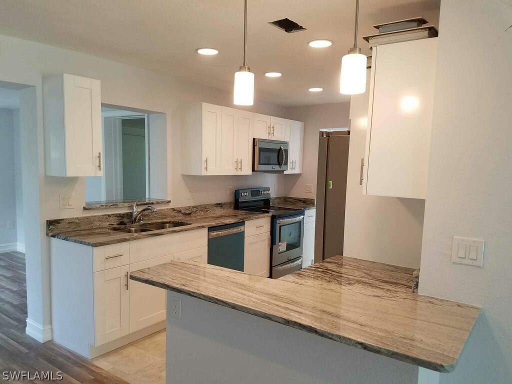 2201 Caladium Road Fort Myers, FL 33905 - Photo 4 of 14 a kitchen with a stove a sink and a refrigerator