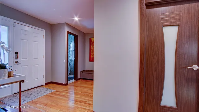a view of a hallway with wooden floor and a bathroom