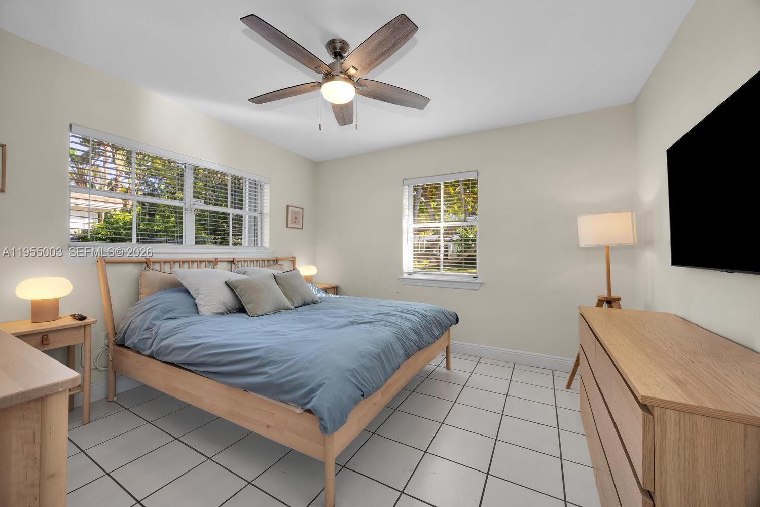 8230 Southwest 63rd Place Miami, FL 33143 - Photo 9 of 24 a bedroom with a large bed a chandelier and a flat tv screen on the dresser