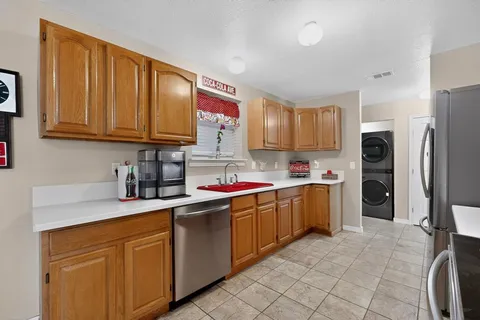 a kitchen with stainless steel appliances granite countertop a stove top oven a sink dishwasher and a refrigerator with wooden cabinets