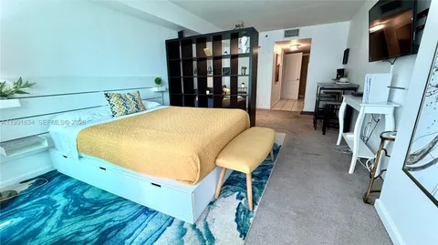 a bed room with a bed tv and a chair