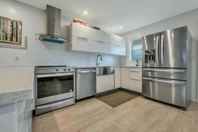 a kitchen with stainless steel appliances kitchen island granite countertop a stove top oven and refrigerator